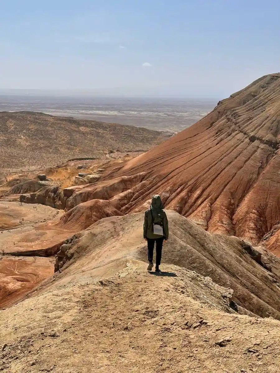 Tourist walking along a ridge of the multicolored Aktau chalk mountains in Altyn-Emel National Park